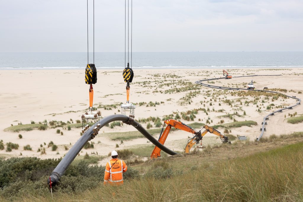 Kabel wordt aan land getakeld op het strand bij de Maasvlakte